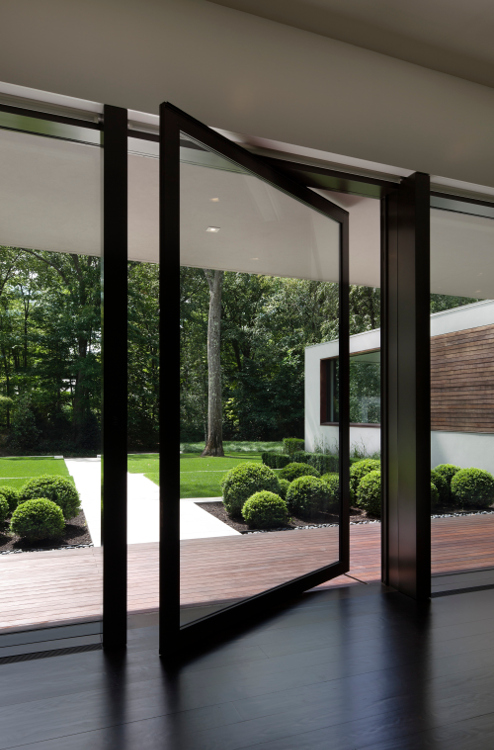 pintu kaca minimalis tanpa handle menghadirkan aksen modern pada fasad rumah