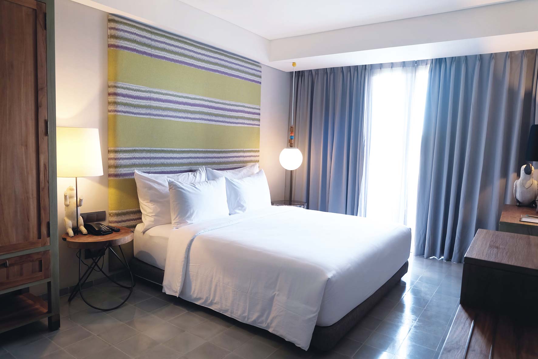 kamar tidur hotel tijili dengan headboard nuansa hijau